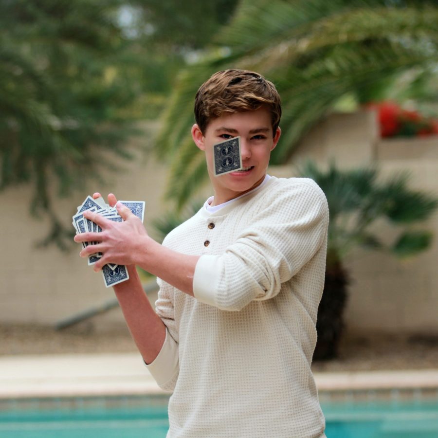 Boy teaching himself magic trick with playing cards