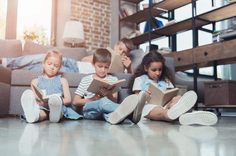 kids sitting on floor reading short moral story books